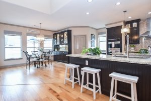 Modern kitchen and dining area in a Houston home, featuring hardwood floors, a granite countertop island with barstools, and dark wood cabinetry, highlighting real estate photography for realtor video tours.