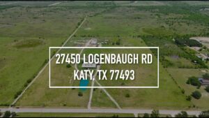 Aerial view of a rural property at 27450 Logenbaugh Rd, Katy, TX 77493, showcasing expansive green fields and a large building, ideal for Houston real estate photography and video tours.